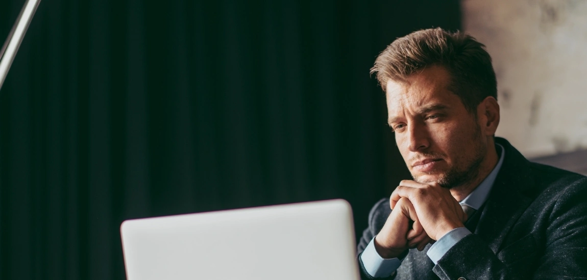 ein nachdenklicher Mann mittleren Alters beim Blick auf seinen Computer, denkt über den Wechsel in die Private Krankenversicherung als Geschäftsführer nach.